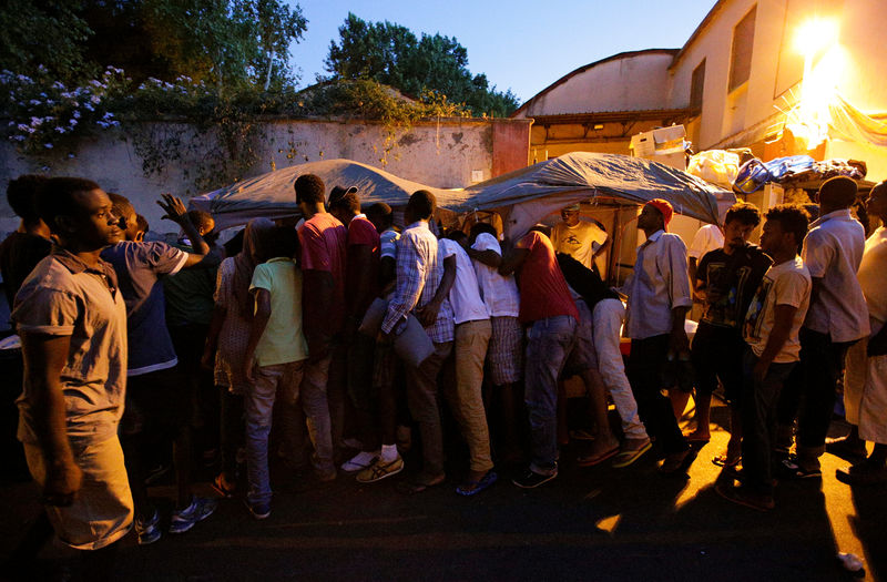 Migrants queue for food at a makeshift camp in Via Cupa (Gloomy Street) in downtown Rome, Italy,