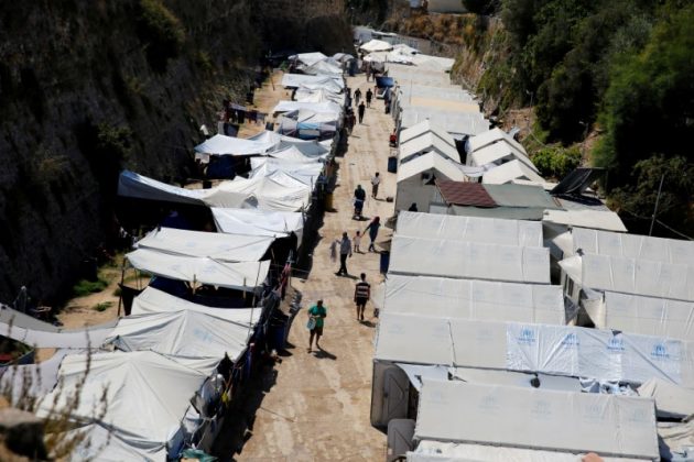 Refugees and migrants make their way at the Souda municipality-run camp, on the island of Chios, Greece