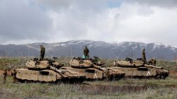 Israeli soldiers stand atop tanks in the Golan Heights near Israel's border with Syria