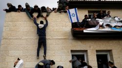 A pro-settlement activist climbs onto a rooftop of a house to resist evacuation of some houses in the settlement of Ofra in the occupied West Bank, during an operation by Israeli forces to evict the houses. REUTERS/Ronen Zvulun