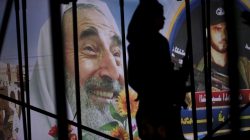 A young Palestinian loyal to Hamas stands under the stage in front of a poster depicting late Hamas spiritual leader Ahmed Yassin (L) during a rally in Khan Younis in the southern Gaza Strip