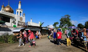 Residents carrying belongings walk past a mosque towards an evacuation center after government troops continued an assault on fighters from the Maute group who have taken over large parts of Marawi city, southern Philippines May 26, 2017. REUTERS/Romeo Ranoco