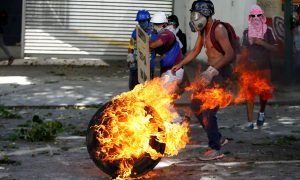 Demonstrators use a tire on fire to block a street at a rally during a strike called to protest against Venezuelan President Nicolas Maduro's government in Caracas, Venezuela July 26, 2017. REUTERS/Andres Martinez Casares