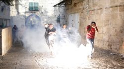 Palestinians react as a stun grenade explodes in a street at Jerusalem's Old city outside the compound known to Muslims as Noble Sanctuary and to Jews as Temple Mount, after Israel removed all security measures it had installed at the compound. REUTERS/Amir Cohen