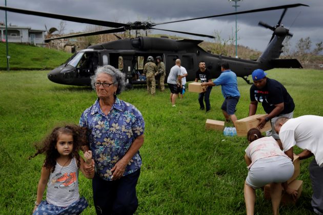 A woman and child walk away as soldiers in a UH-60 Blackhawk helicopter from the First Armored Division's Combat Aviation Brigade deliver food and water during recovery efforts following Hurricane Maria in Verde de Comerio, Puerto Rico, October 7, 2017. REUTERS/Lucas JacksonA woman and child walk away as soldiers in a UH-60 Blackhawk helicopter from the First Armored Division's Combat Aviation Brigade deliver food and water during recovery efforts following Hurricane Maria in Verde de Comerio, Puerto Rico, October 7, 2017. REUTERS/Lucas Jackson