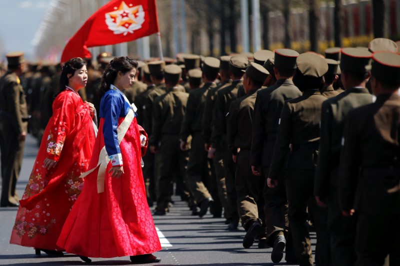 Women wearing traditional clothes walk past North Korean soldiers after an opening ceremony for a newly constructed residential complex in Ryomyong street in Pyongyang, North Korea April 13, 2017.