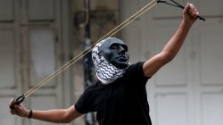 A Palestinian demonstrator uses a slingshot to hurl stones towards Israeli troops during clashes at a protest as Palestinians call for a "Day of Rage" in response to U.S. President Donald Trump's recognition of Jerusalem as Israel's capital, in the West Bank city of Hebron December 22, 2017.