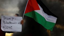 A demonstrator holds a sign and a Palestinian flag during clashes with Israeli troops at a protest against U.S. President Donald Trump's decision to recognise Jerusalem as the capital of Israel, near the West Bank city of Nablus, December 29, 2017.