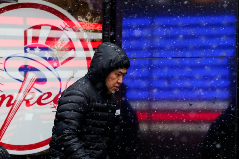 A man walks in falling snow at Times Square as a cold weather front hits the region, in Manhattan, New York, U.S., December 30, 2017.