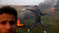 A Palestinian demonstrator hurls stones towards Israeli troops during clashes, near the border with Israel in the east of Gaza City January 12, 2018.