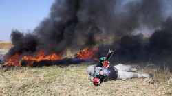 A Palestinian hurls stones at Israeli troops during clashes at the Gaza-Israel border at a protest demanding the right to return to their homeland, in the southern Gaza Strip March 31, 2018. REUTERS/Ibraheem Abu Mustafa