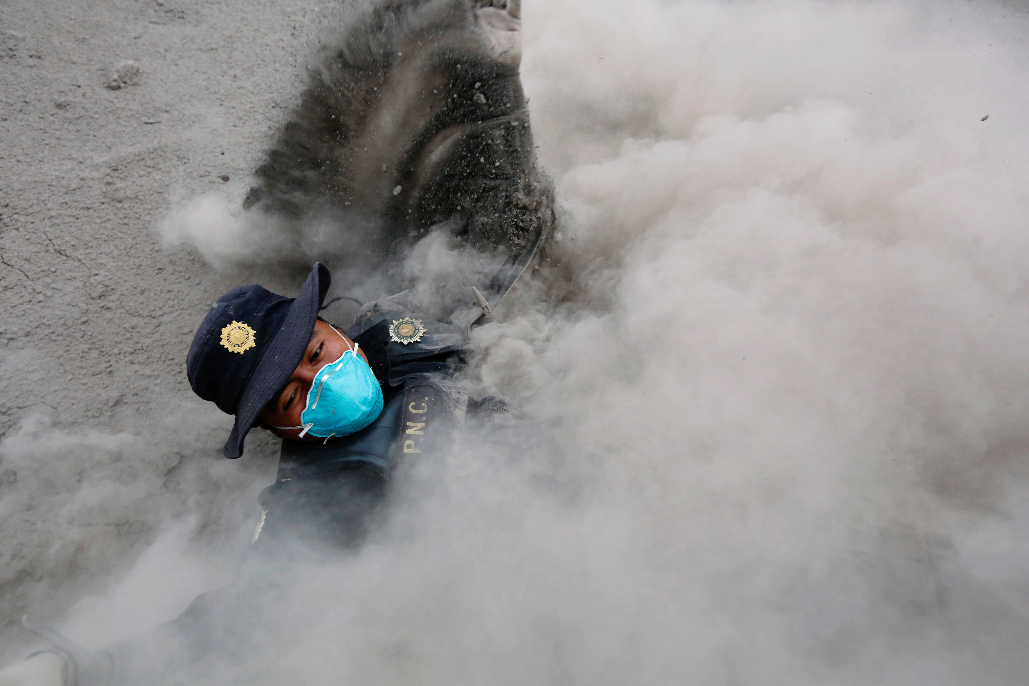 A police officer stumbles while running away from a new pyroclastic flow spewed by the Fuego volcano in the community of San Miguel Los Lotes in Escuintla, Guatemala, June 4, 2018. REUTERS/Luis Echeverria