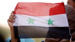 FILE PHOTO: A woman holds a Syrian flag in Deraa, Syria, July 4, 2018. REUTERS/Omar Sanadiki/File Photo