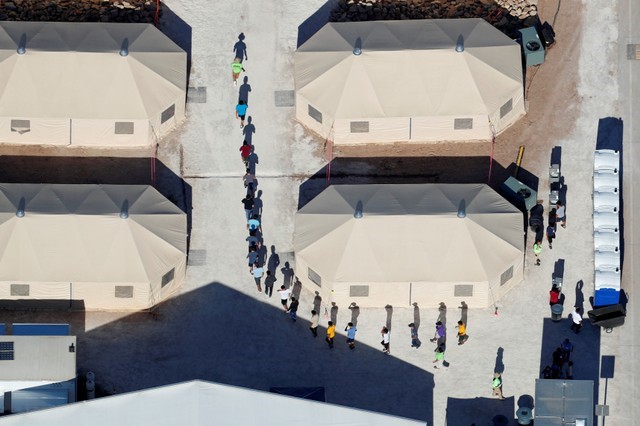 FILE PHOTO: Immigrant children, many of whom have been separated from their parents under a new "zero tolerance" policy by the Trump administration, are shown walking in single file between tents in their compound next to the Mexican border in Tornillo, Texas. REUTERS/Mike Blake