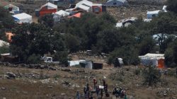 People wave white cloths next to the refugee tents erected near the border fence between Israel and Syria from its Syrian side as it is seen from the Israeli-occupied Golan Heights near the Israeli Syrian border July 17, 2018. REUTERS/Ronen Zvulun