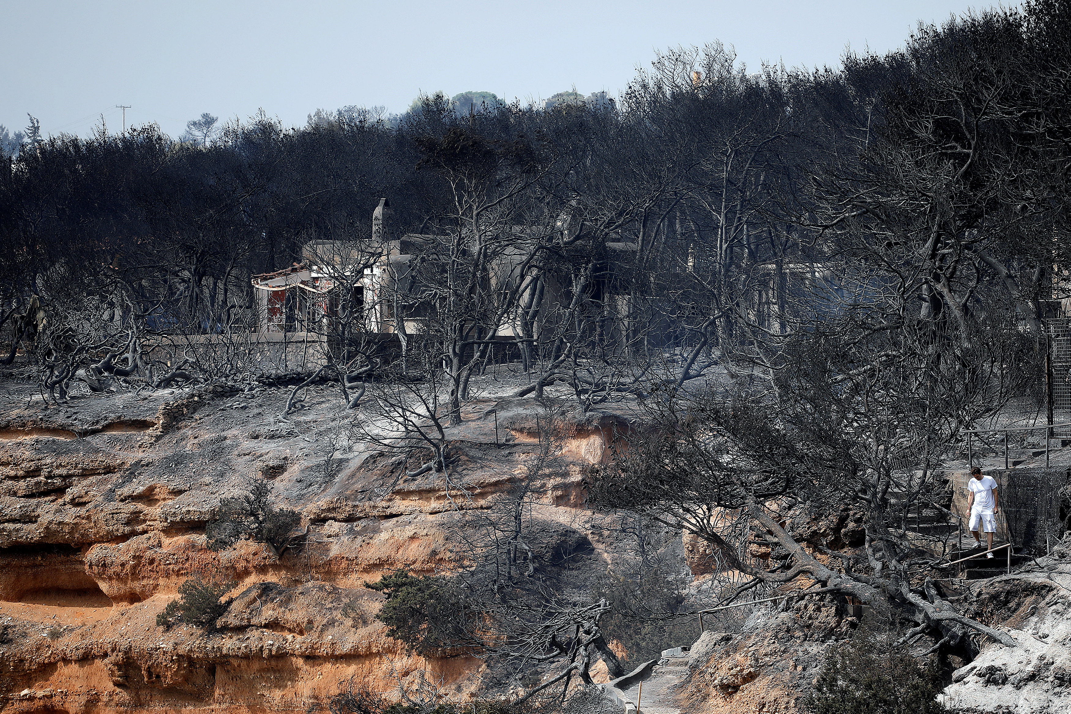 FILE PHOTO: A local walks on a burnt slope following a wildfire at the village of Mati, near Athens, Greece, July 24, 2018. REUTERS/Alkis Konstantinidis/File Photo