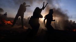 Palestinians hurl stones at Israeli troops during a protest calling for lifting the Israeli blockade on Gaza and demanding the right to return to their homeland, at the Israel-Gaza border fence, in the southern Gaza Strip September 21, 2018. REUTERS/Ibraheem Abu Mustafa
