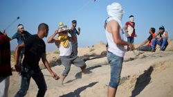 FILE PHOTO: A Palestinian protester covers his head with a model of the Dome of the Rock during clashes with Israeli troops near the border between Israel and Central Gaza Strip August 4, 2017. REUTERS/Ibraheem Abu Mustafa