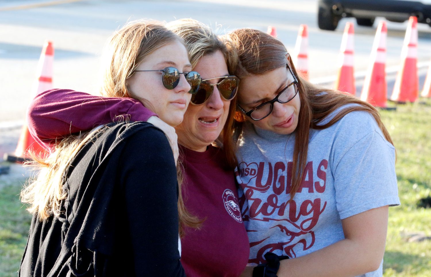 Cheryl Rothenberg embraces her daughters Emma and Sophia as they view a memorial on the one year anniversary of the shooting which claimed 17 lives at Marjory Stoneman Douglas High School in Parkland, Florida, U.S., February 14, 2019. Sophia is a student at the school and Emma is a recent graduate. REUTERS/Joe Skipper