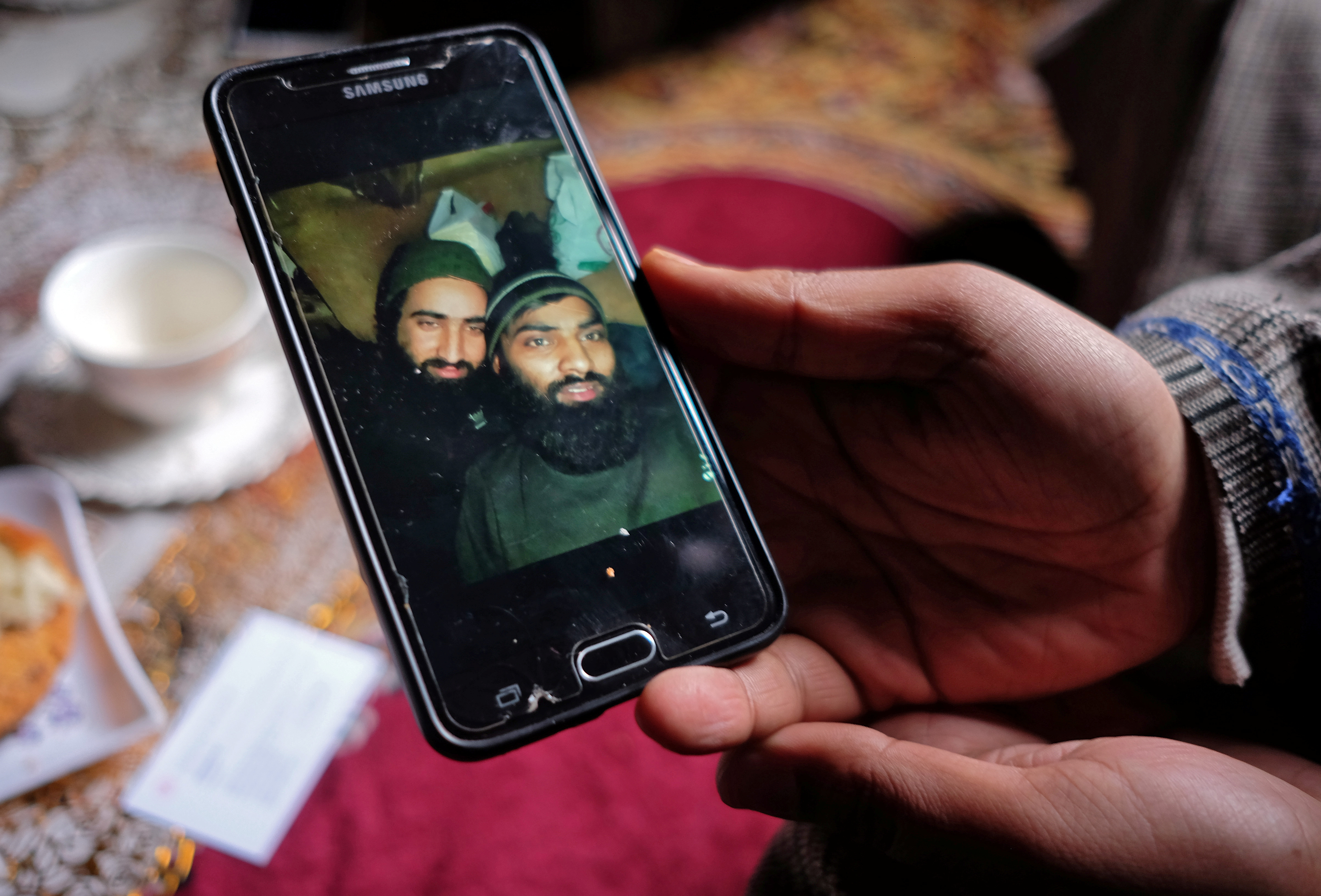 Bilal Ahmad Naikoo, a civilian, displays a photo of his brother Hilal with Rashid Bhai, a Pakistani national, both members of Pakistan-based militant group Jaish-e-Mohammed (JeM), who were killed in a gun battle with Indian army in Pinglan village in south Kashmir's Pulwama district March 21, 2019. REUTERS/Stringer