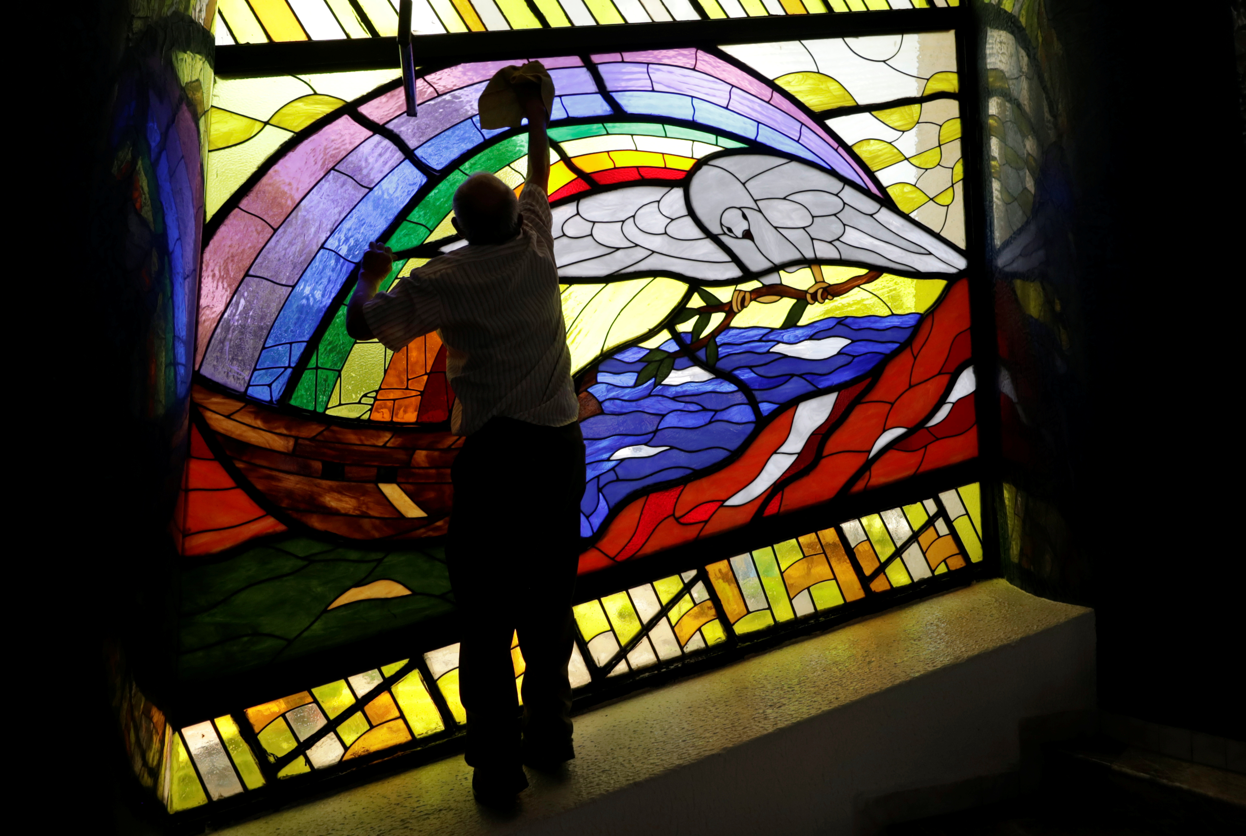 A man cleans a stained glass inside a La Luz del Mundo (The Light of the World) church after its leader Naason Joaquin Garcia was arrested in California, in Mexico City, Mexico June 5, 2019. REUTERS/Luis Cortes