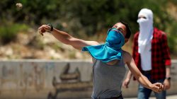 A Palestinian boy hurls stones at Israeli forces during clashes at a protest against Bahrain's workshop for U.S. peace plan, near Hebron, in the Israeli-occupied West Bank June 24, 2019. REUTERS/Mussa Qawasma